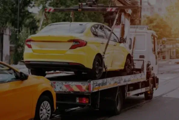 Carro amarelo preso sobre a plataforma de um guincho. Imagem ilustrativa.